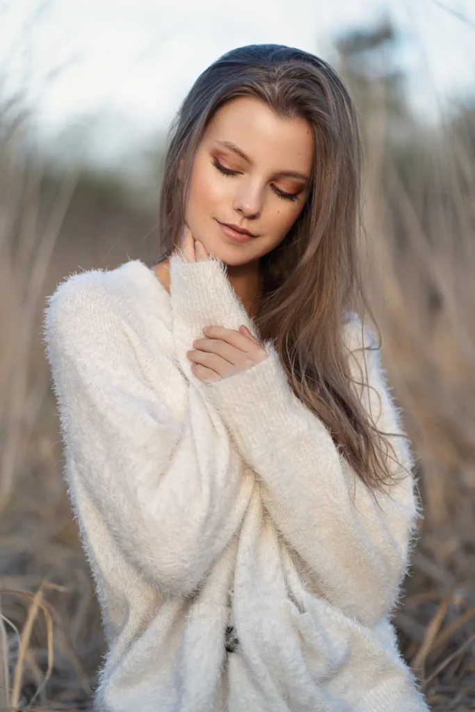 zdjecie dziewczyny z dlugimi wlosami w bialym swetrze w trawie tomaszroman fotografia portretowa kobieca mragowo olsztyn mazury